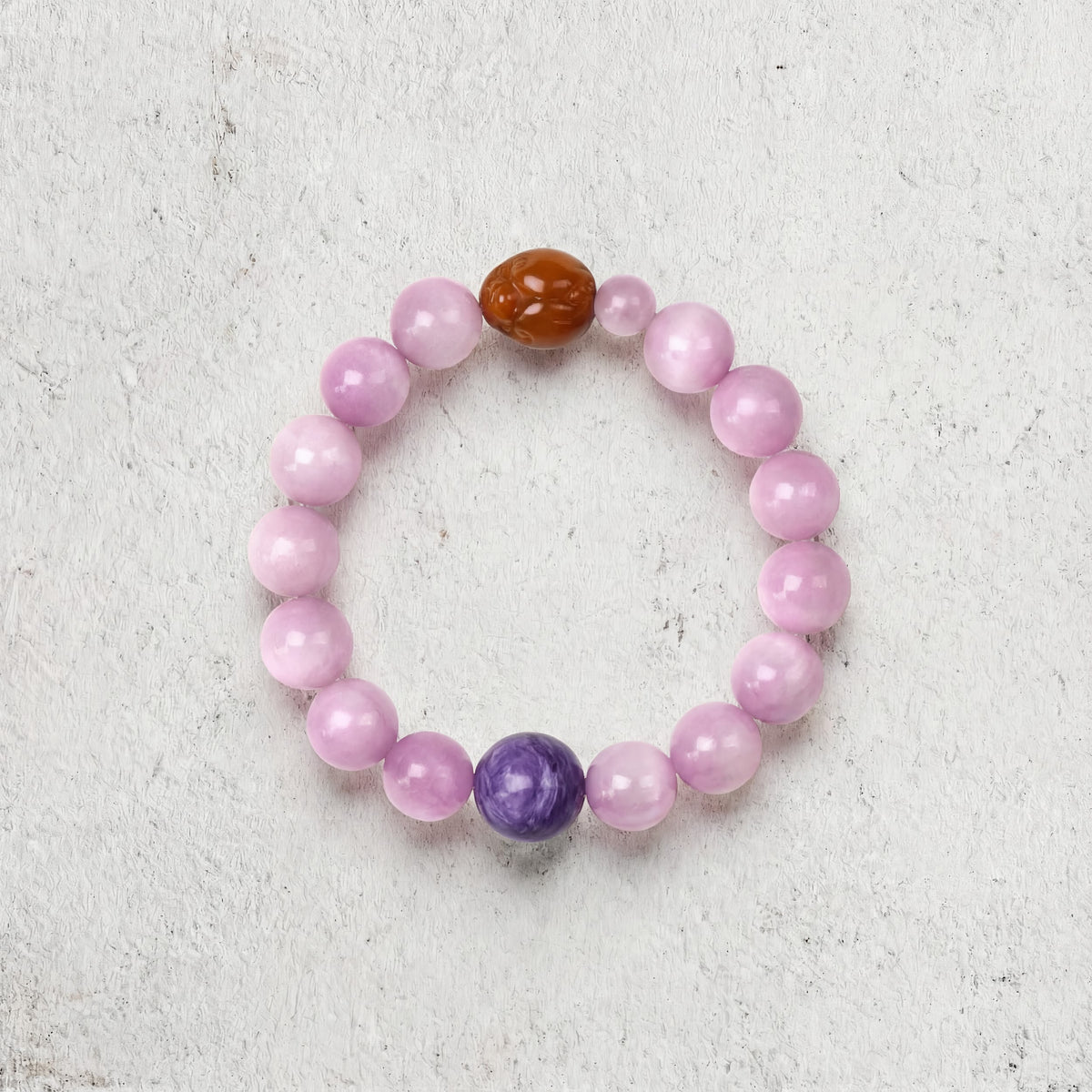 Z04 Violet Static bracelet top-down on light gray — soft pink kunzite with a purple charoite bead