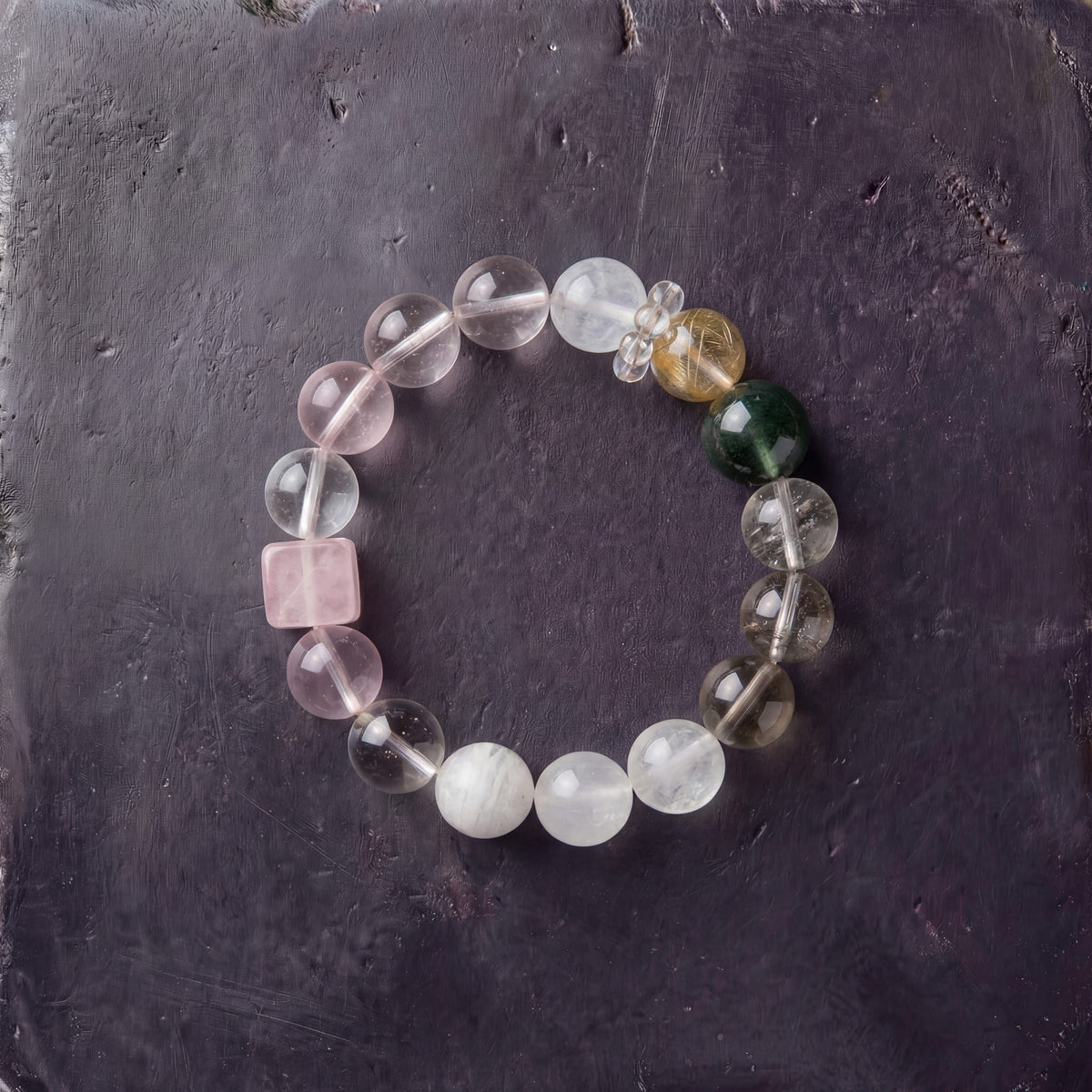 Z07 Rose Protocol bracelet — milky white and rose quartz beads with a pink cube and jade accent, flat lay on dark stone