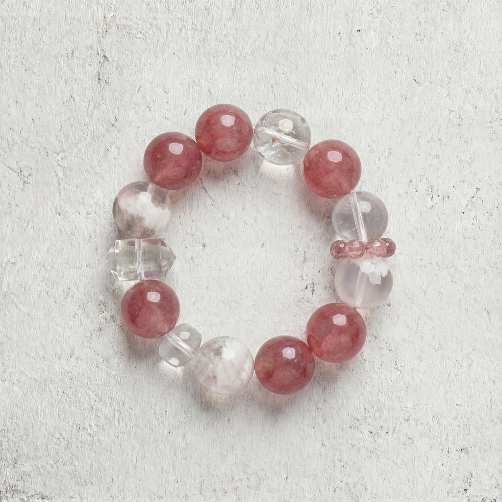 Z05 Rouge Kinetic bracelet top-down on light gray — speckled strawberry quartz and clear beads